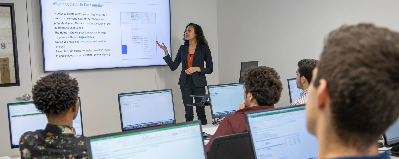 An instructor teaching a small in-person class at workstations